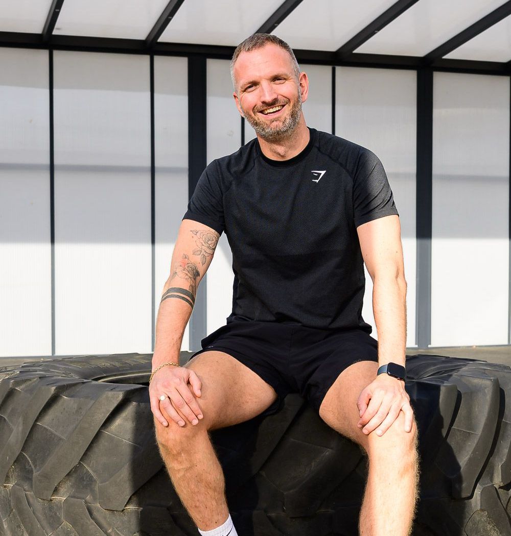 Pieter in sportkleding, lachend op een grote tractorband